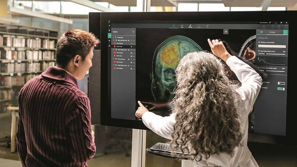 Two people looking at a medical image on a large display