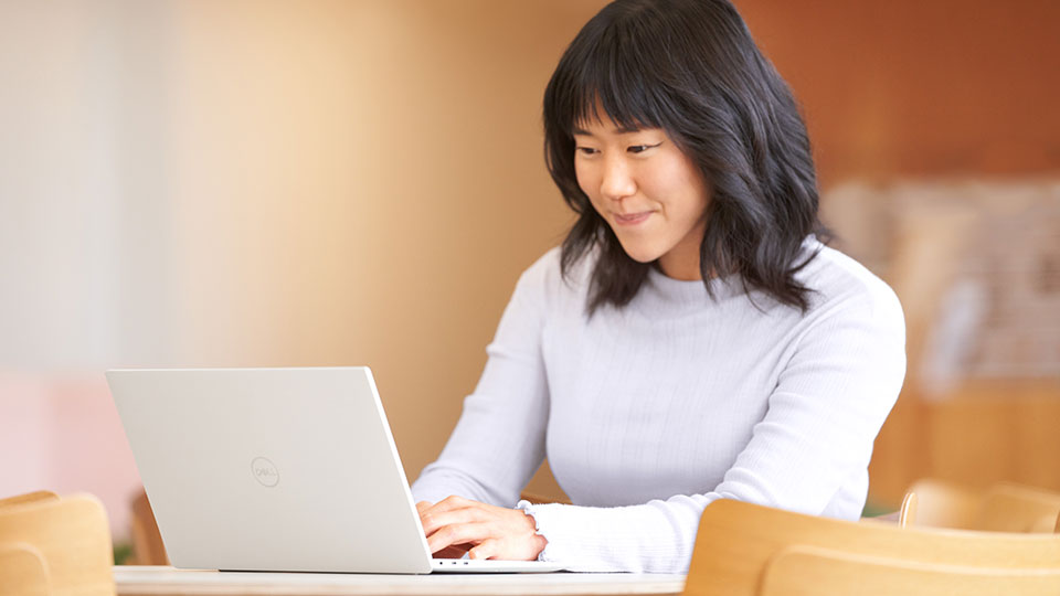 A smiling woman typing on a laptop