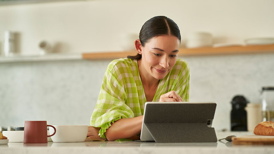 A woman uses a tablet at her kitchen table